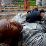 A cadet crawls through a sandpit under strings of barbed wire during an obstacle course at LDAC.