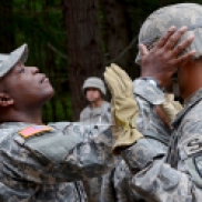 An officer checks a cadets helmet before sending up to the rappel wall.